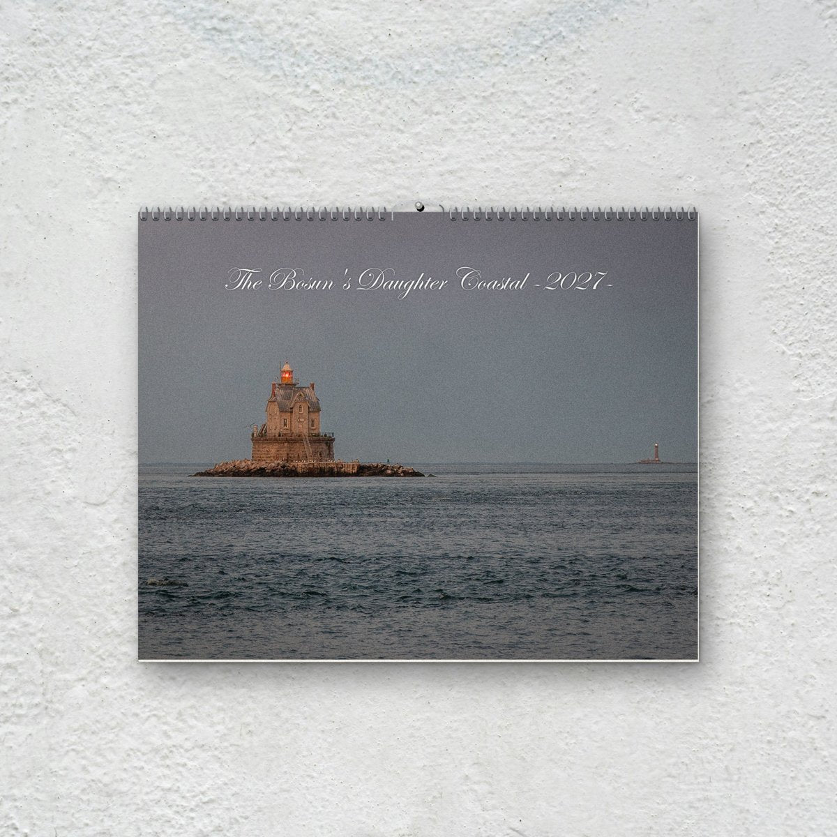 Coastal 2027 wall calendar hanging on a white plaster wall